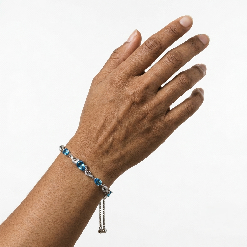 Close-up of the blue topaz tennis bracelet worn on a raised wrist against a plain background.