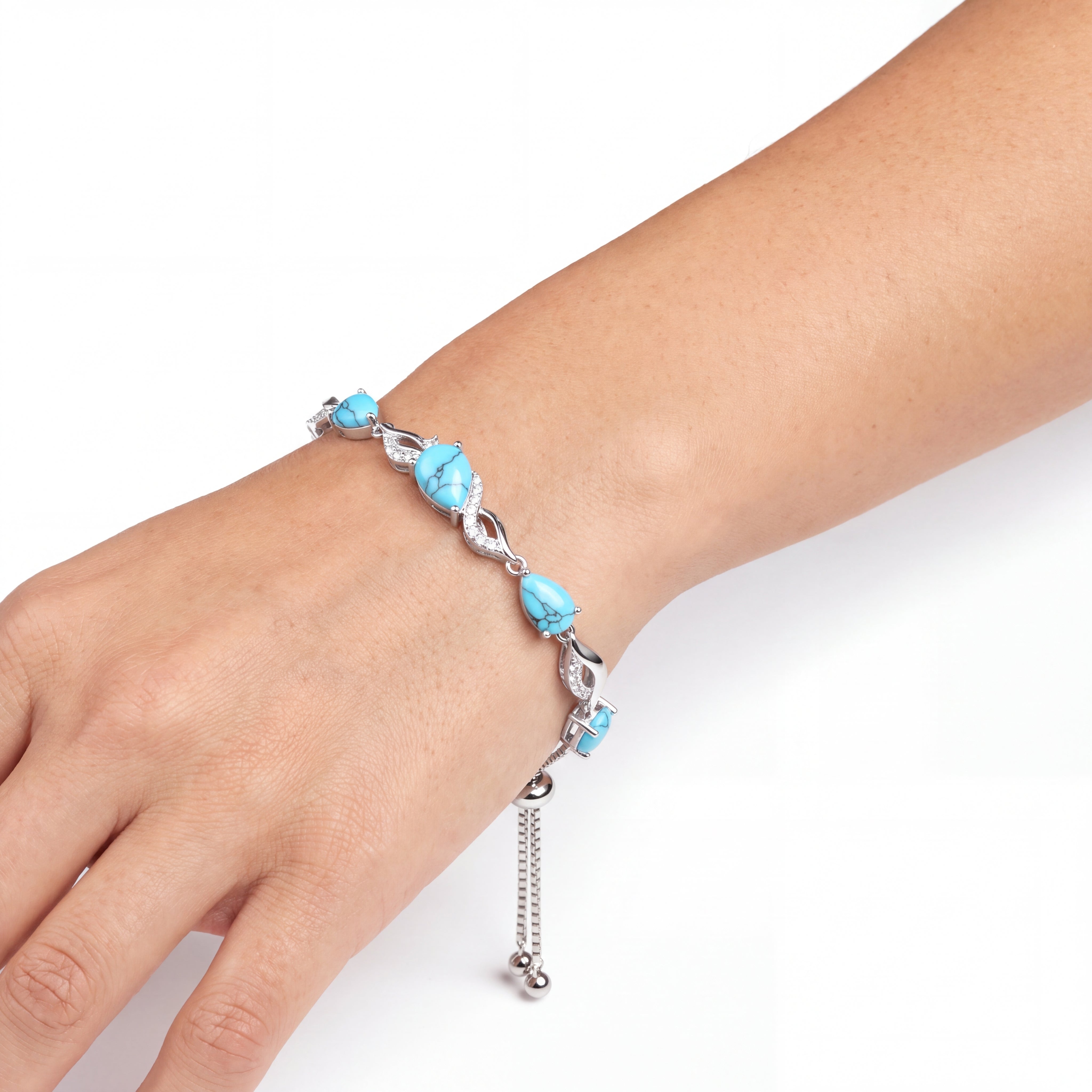 Close-up of the turquoise tennis bracelet worn on a wrist against a plain background.