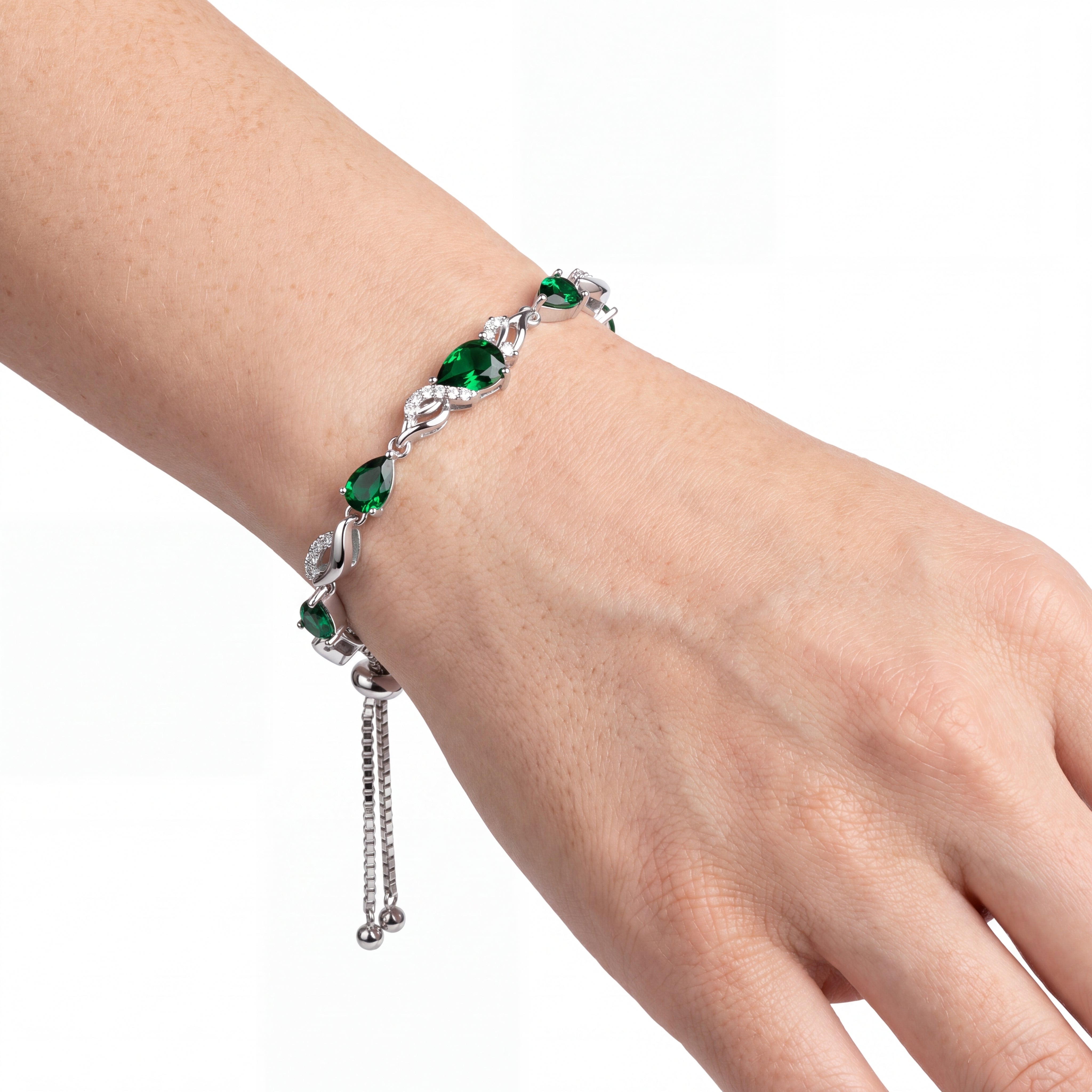 Emerald tennis bracelet worn on the wrist, close-up angled view