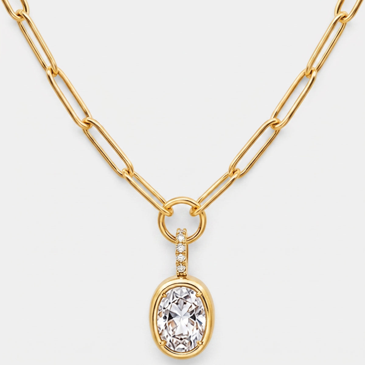 Clear oval CZ bezel pendant with a pave bail on an 18K gold plated paperclip chain necklace