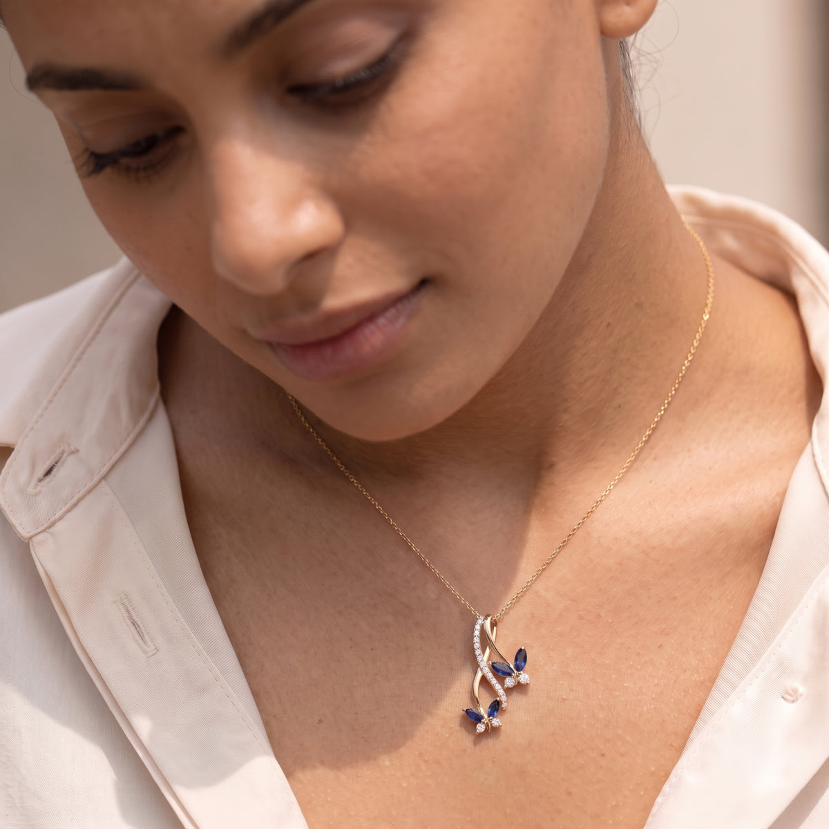 Close-up of a butterfly infinity necklace with marquise blue sapphire wings at the collarbone