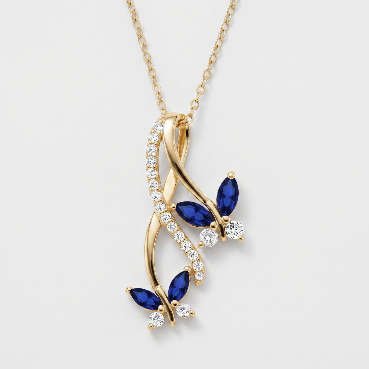 Gold tone butterfly infinity pendant necklace with blue created sapphire wings and white CZ stones