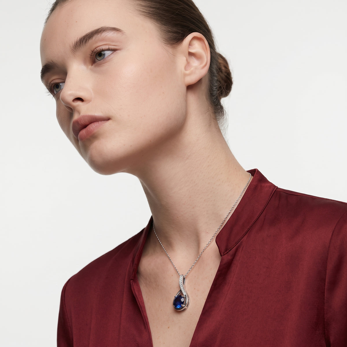 Woman wearing a silver sapphire pendant necklace on a thin cable chain