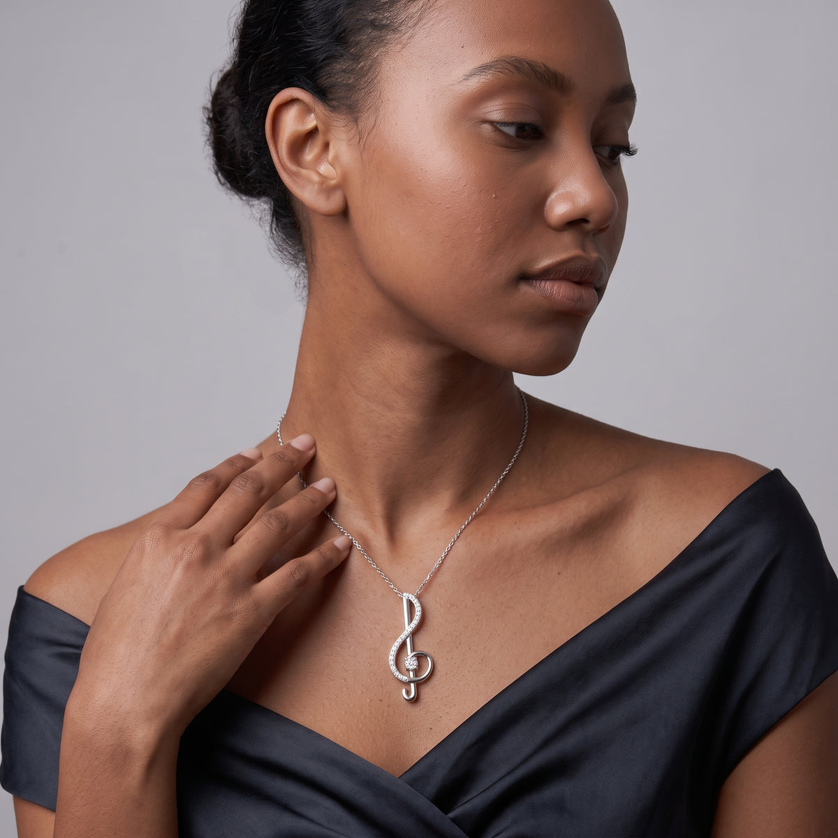 Woman wearing a dainty sterling silver music note necklace on a thin cable chain