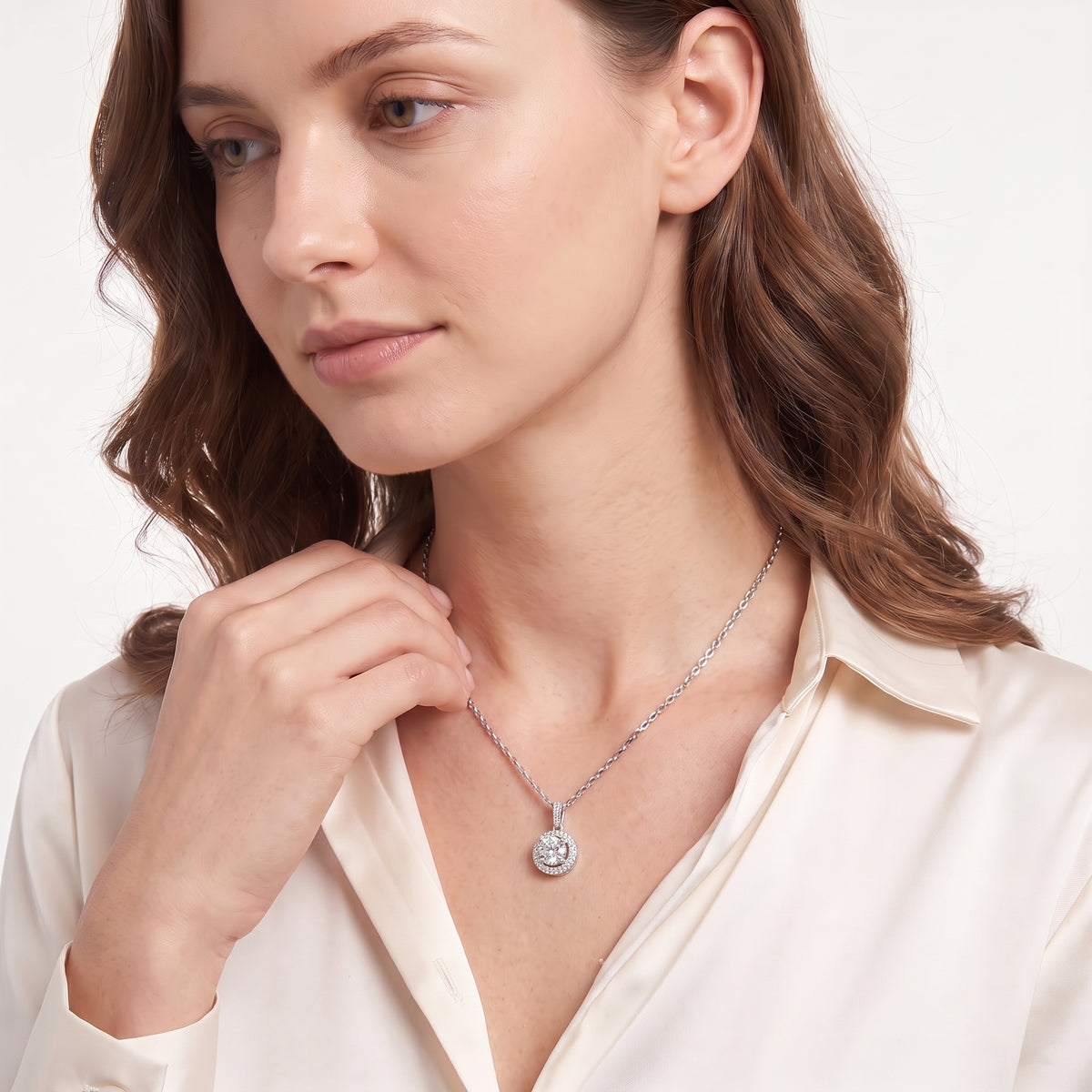 Woman in a cream blouse wearing a sterling silver moissanite halo necklace