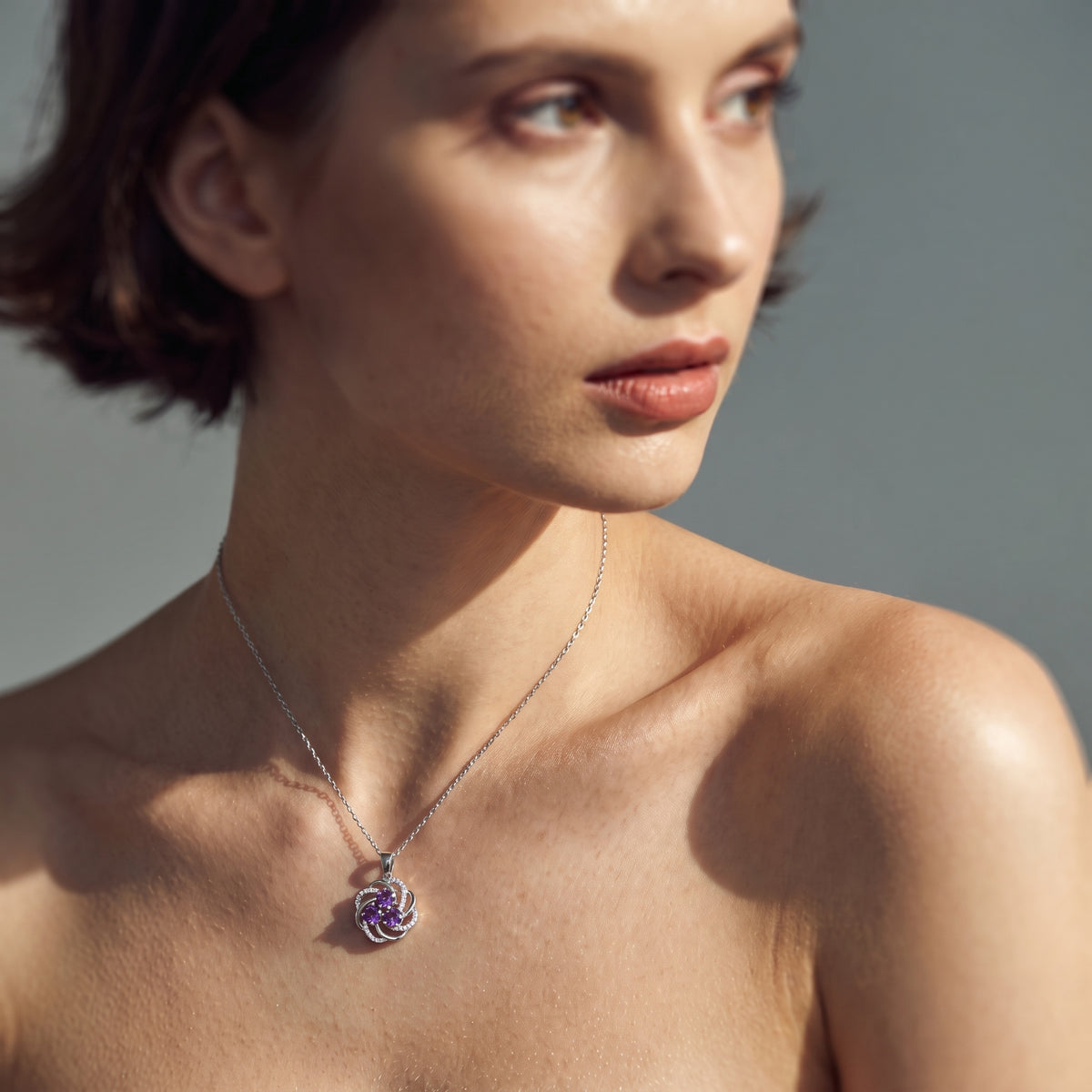 Side view of a woman wearing a February birthstone amethyst pendant necklace