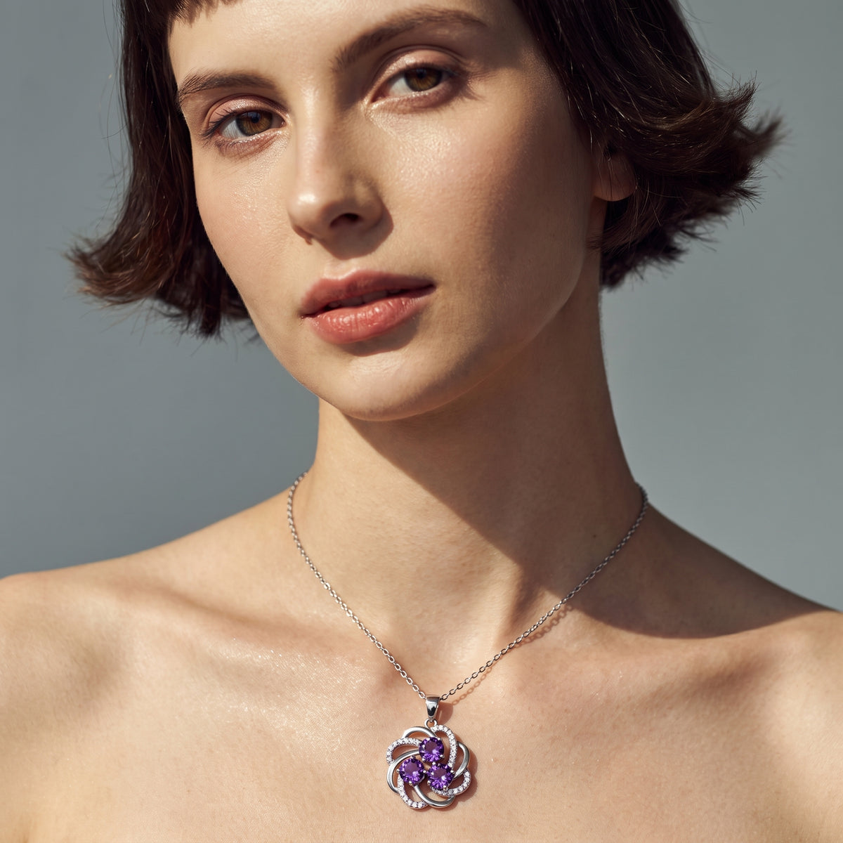 Woman with short dark hair wearing a purple amethyst three stone necklace