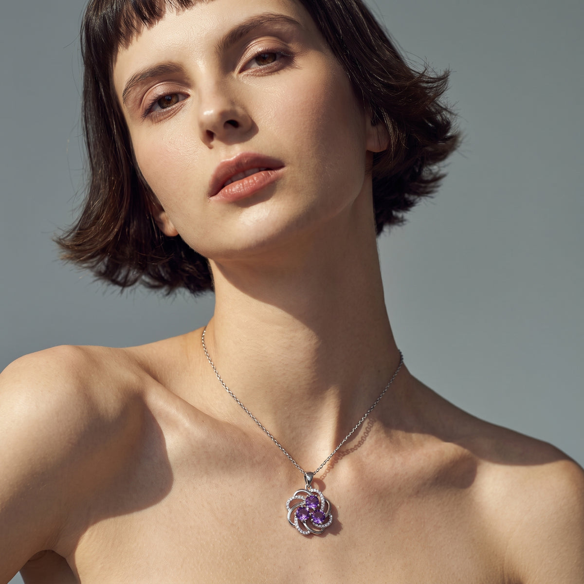 Amethyst pinwheel pendant resting on the collarbone on a thin silver chain