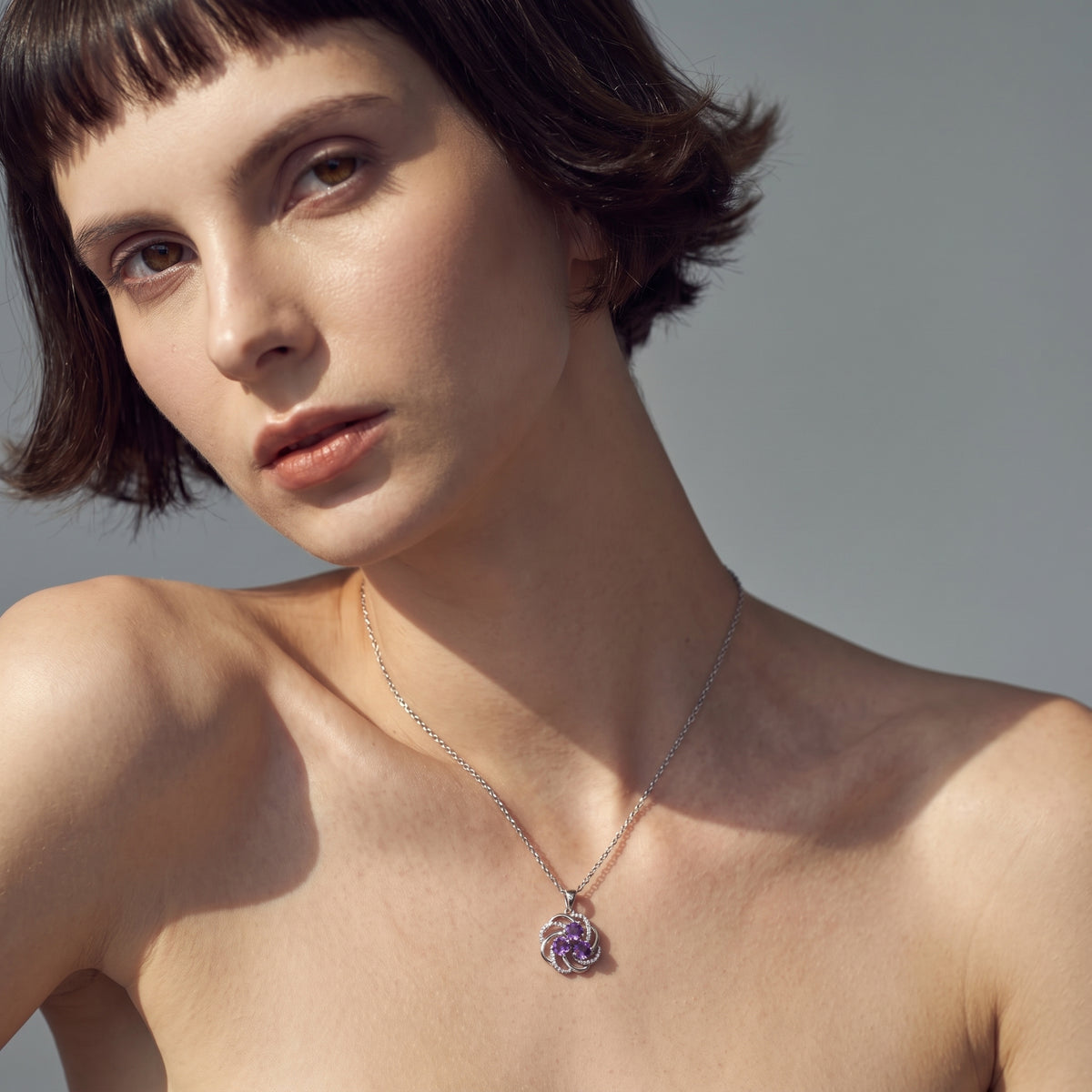 Woman looking over her shoulder wearing a sterling silver amethyst pendant