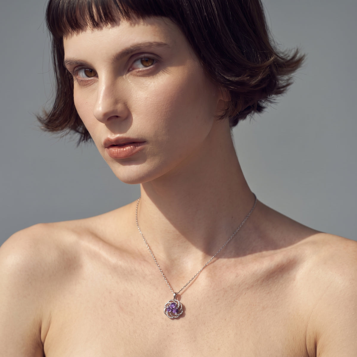 Close portrait of a woman wearing a three stone purple amethyst necklace