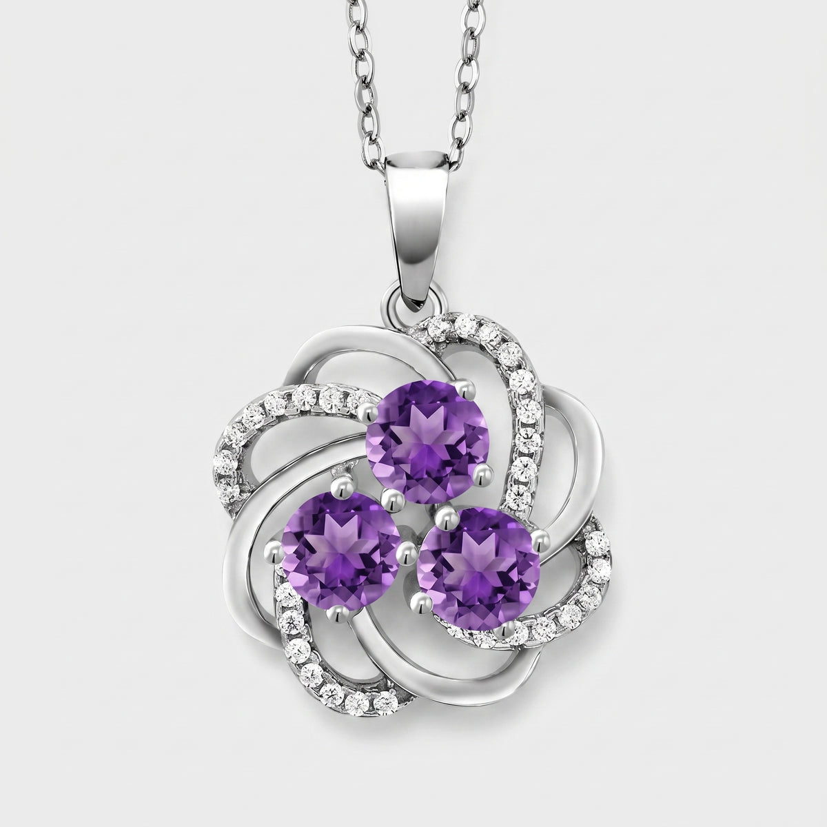 Sterling silver pinwheel pendant with three round natural amethysts and white CZ accents