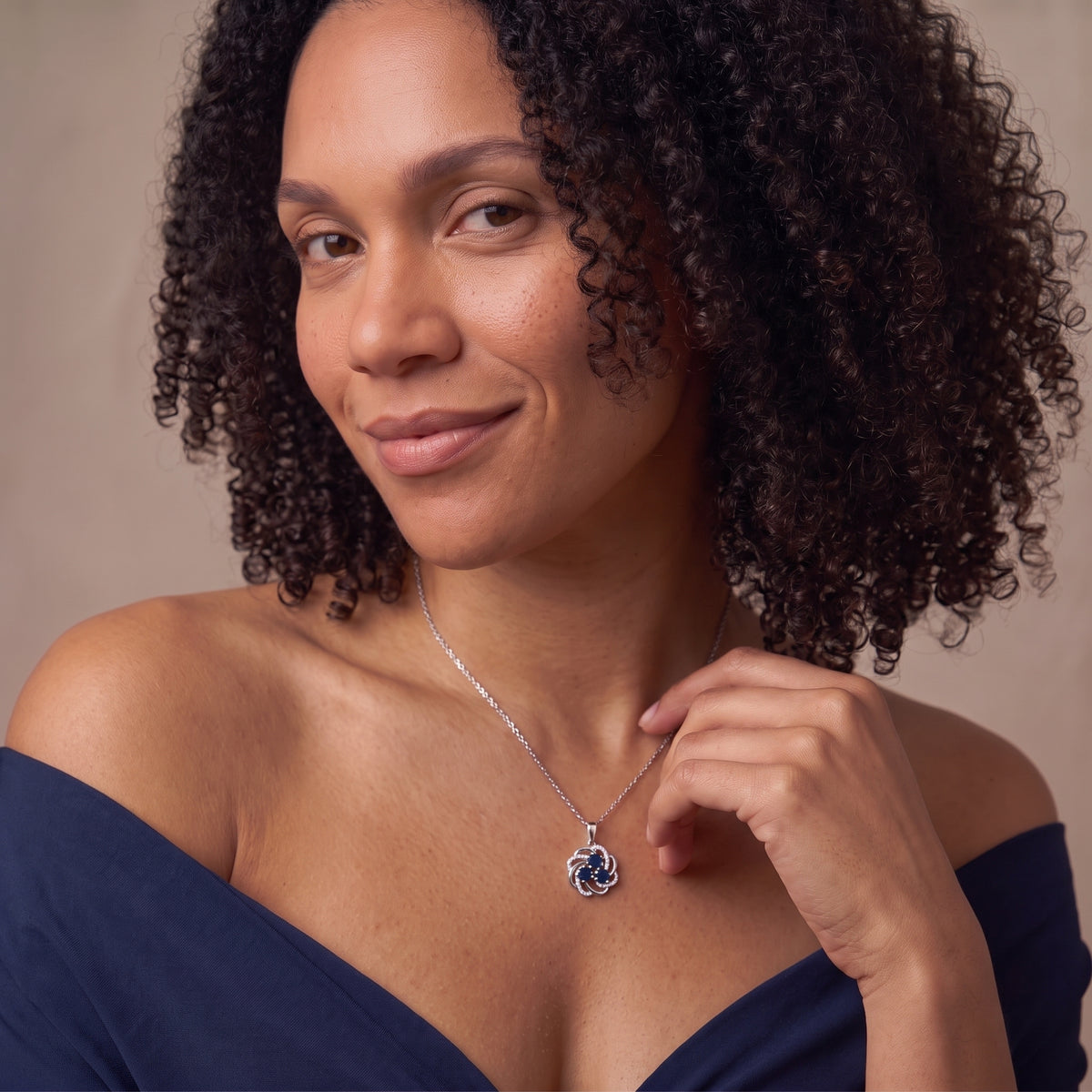 Smiling woman touching a sapphire blossom pendant on a thin silver chain