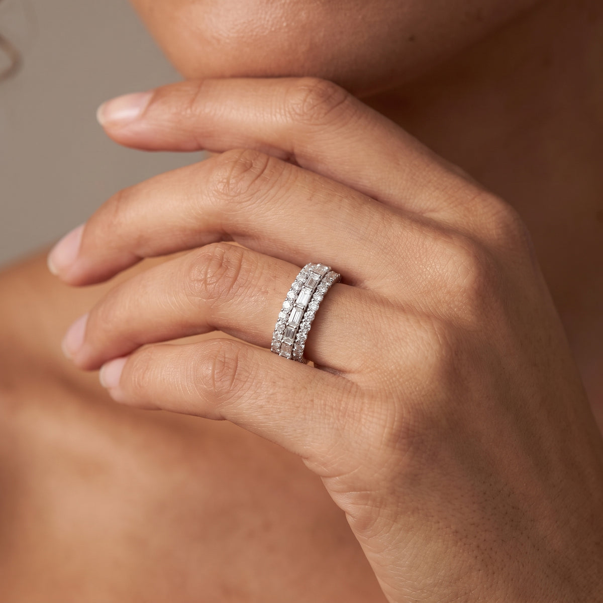 Close view of a hand under the chin wearing a round and baguette lab created diamond band