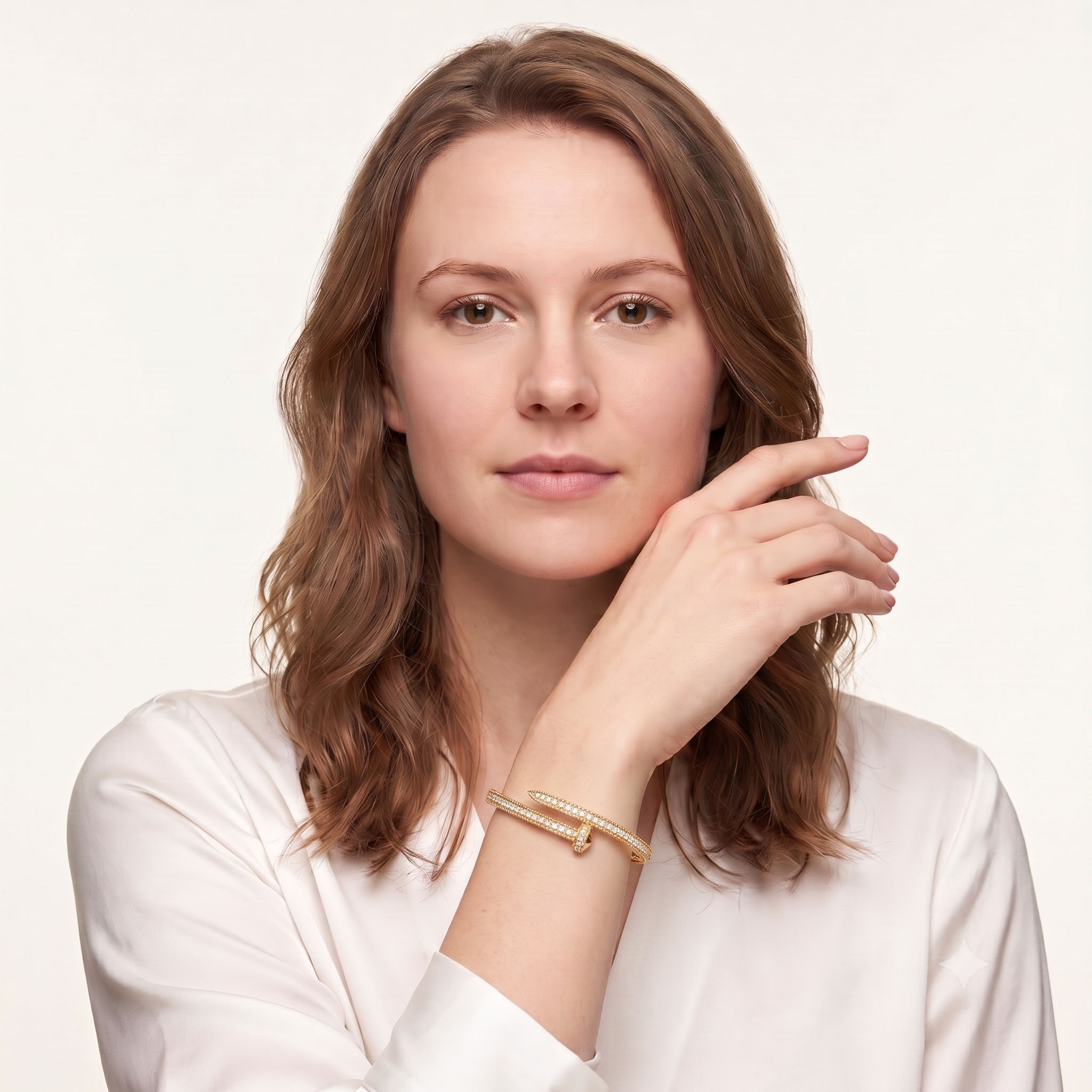 Gold plated pave nail bracelet worn on the wrist with a soft cream silk shirt