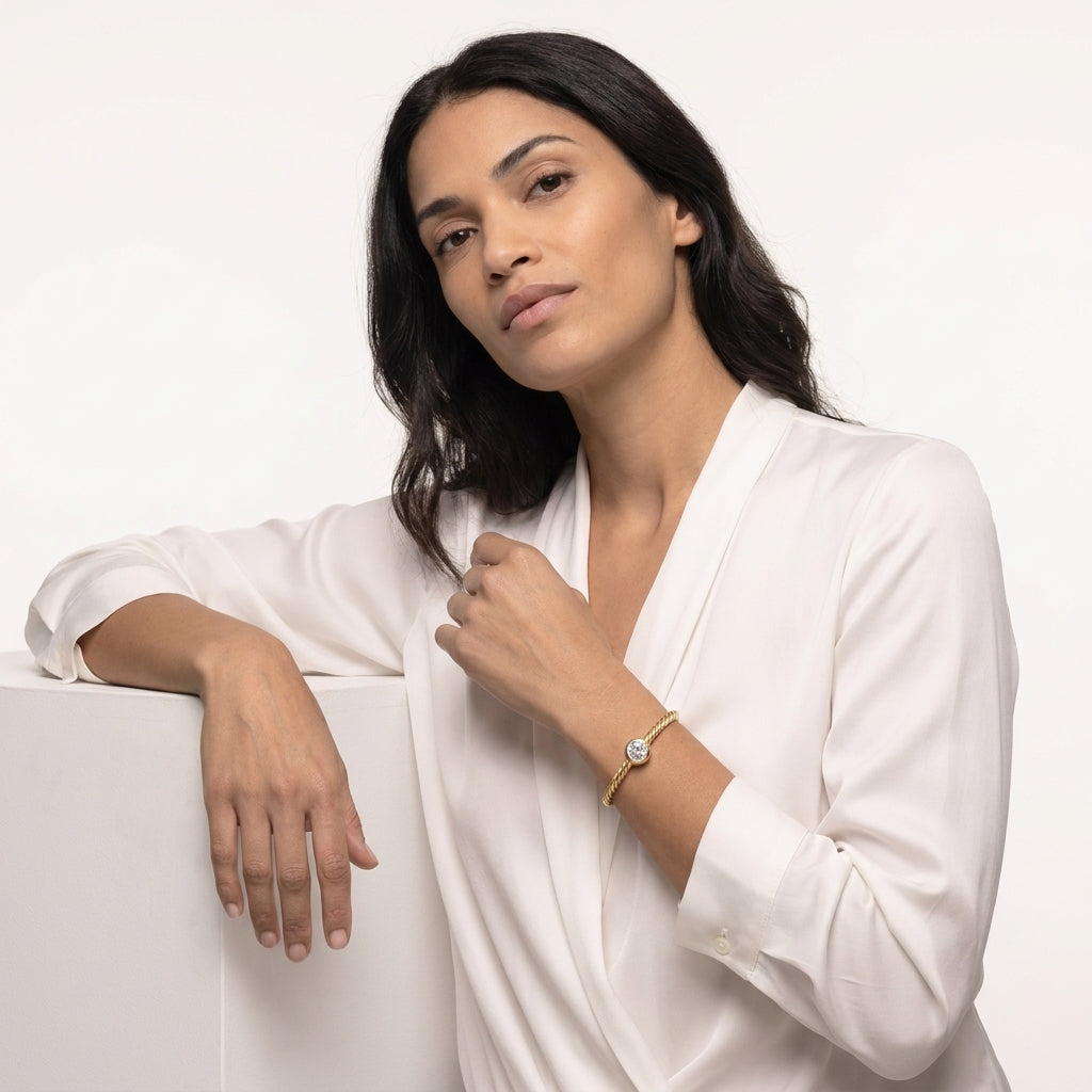 Model seated in a white shirt wearing the gold plated cable bracelet with a single cubic zirconia stone