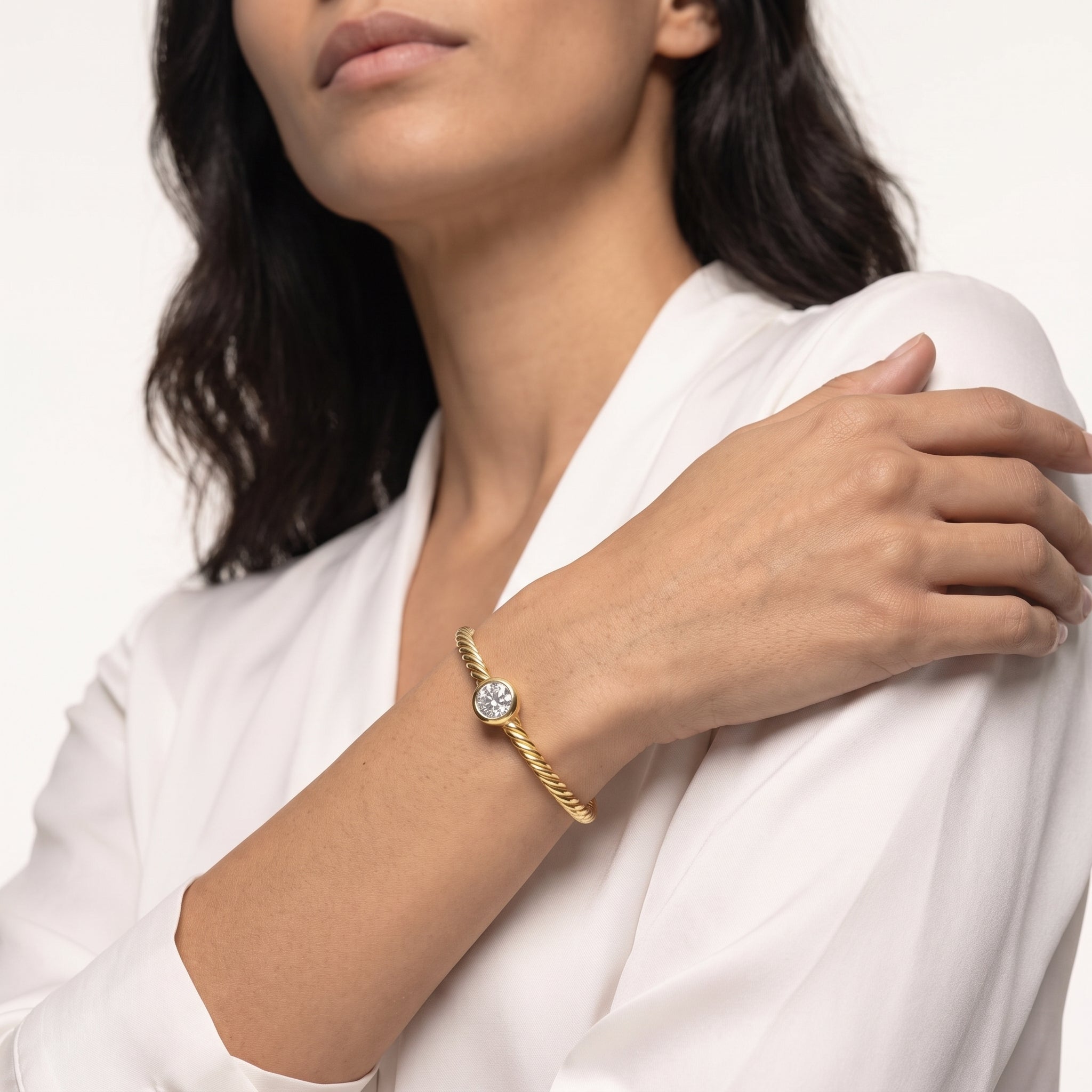 18K gold plated twisted cable bracelet with a 6mm bezel set cubic zirconia shown on the wrist