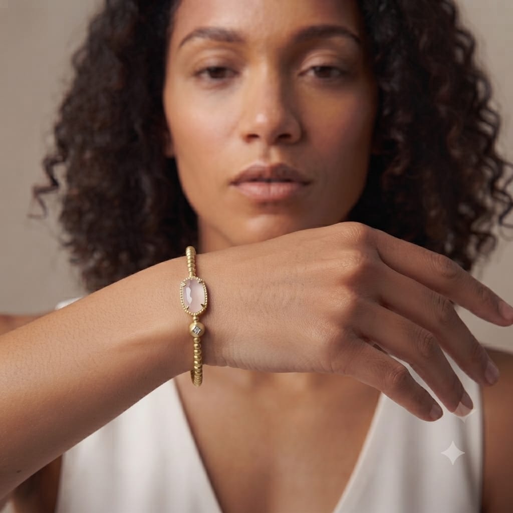 Close view of a gold beaded stretch bracelet with a faceted rose quartz center stone
