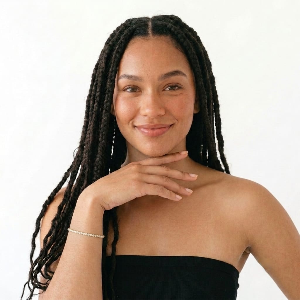 Full view of a woman wearing a slim 3mm gold tennis bracelet with a black top
