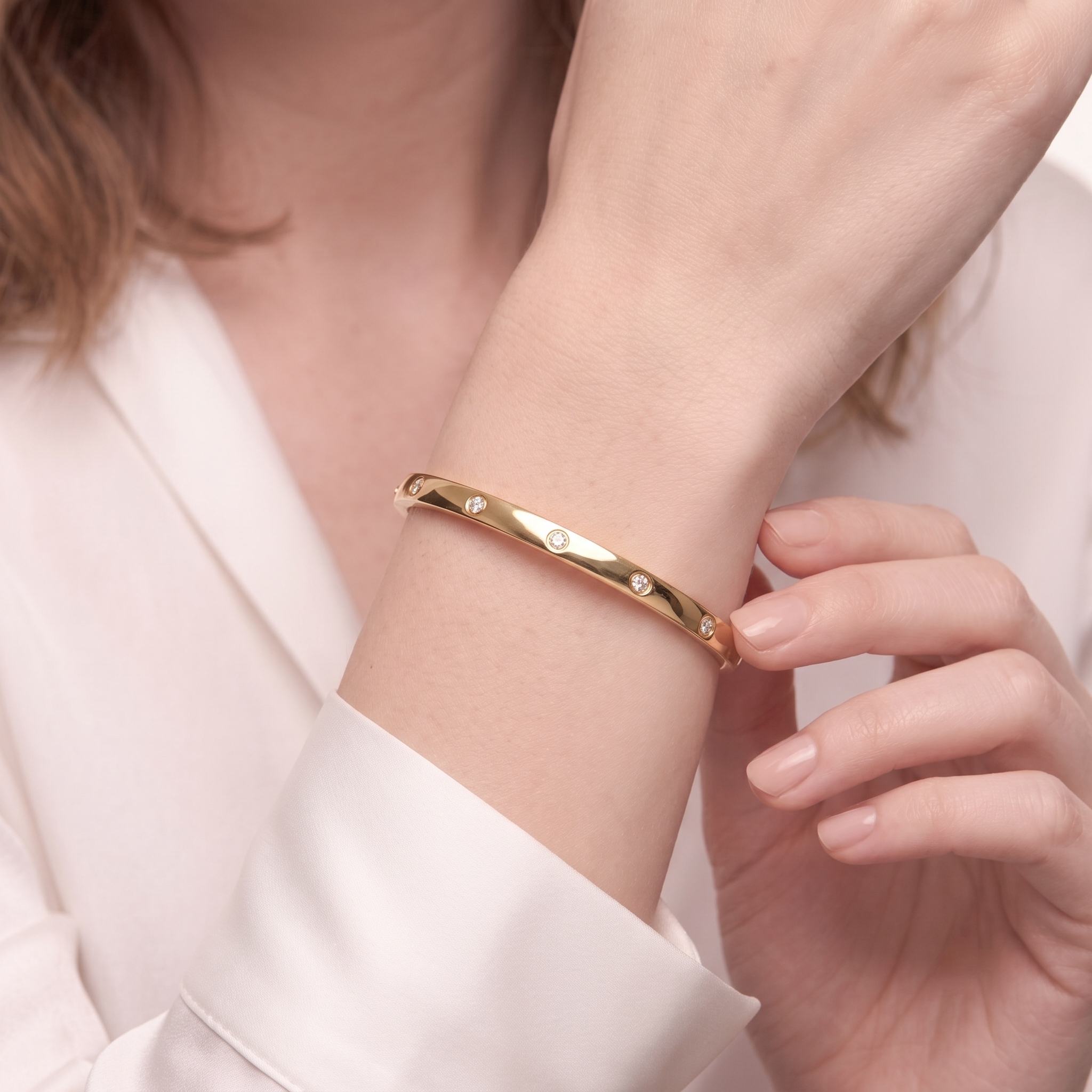 Woman wearing the 14K gold plated stackable round cubic zirconia bangle bracelet, close-up on wrist