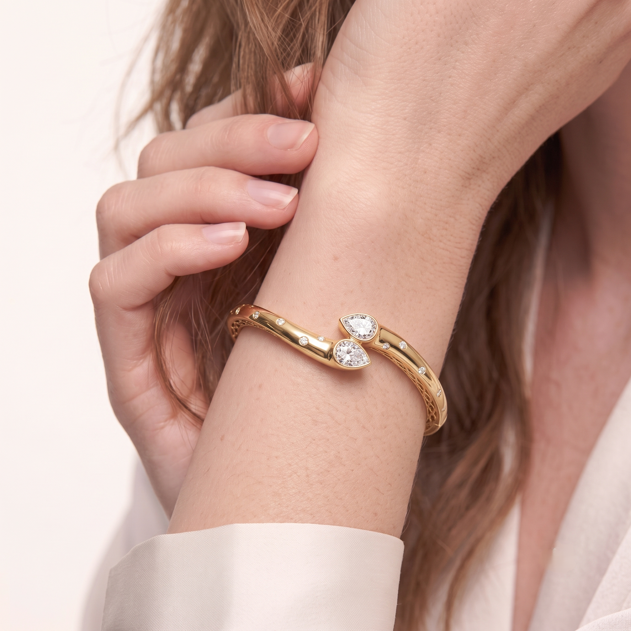 Woman wearing the 14K gold plated double pear cubic zirconia bangle bracelet, close-up on wrist