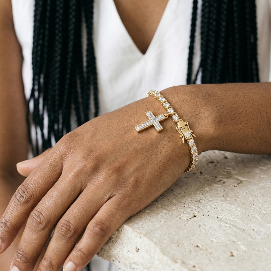 Gold cross charm bracelet with a pave set cross and box clasp shown on a wrist