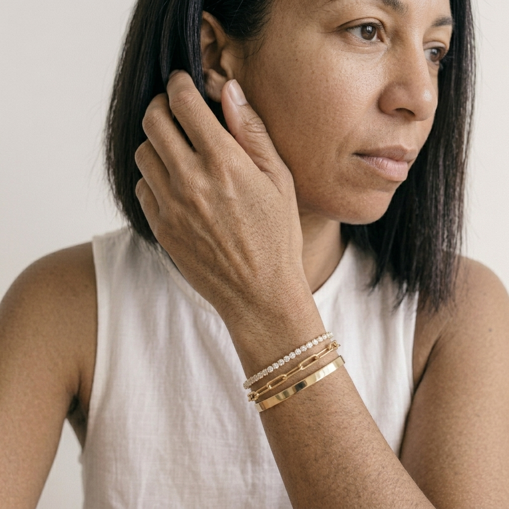 Woman wearing a layered 3 piece gold plated bracelet set with a white top
