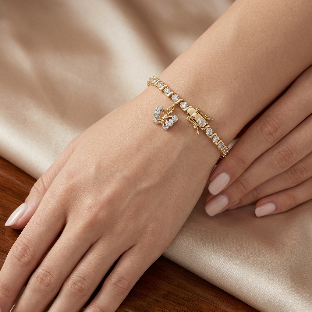 Gold butterfly charm bracelet with pave set wings and a box clasp shown on a wrist