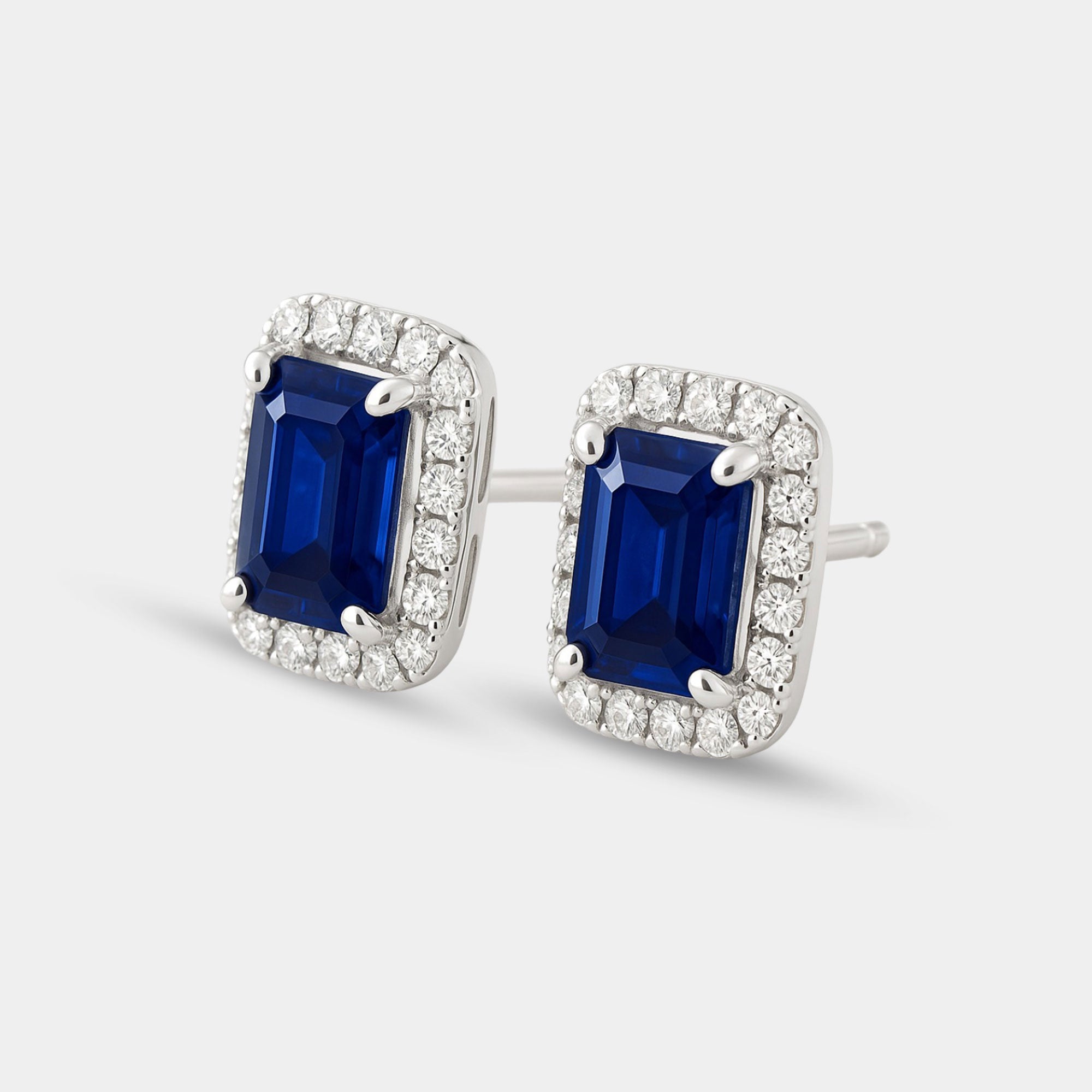 Pair of sterling silver blue sapphire halo studs shown with push-back posts for sensitive ears