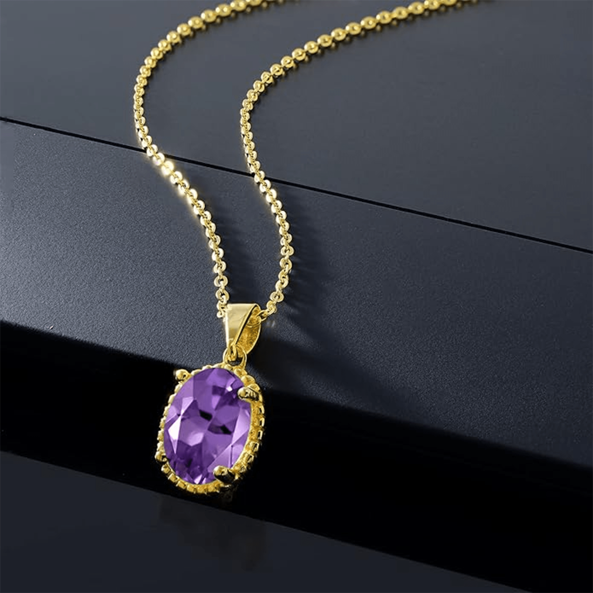 Amethyst oval pendant necklace with a gold chain styled on a dark reflective surface