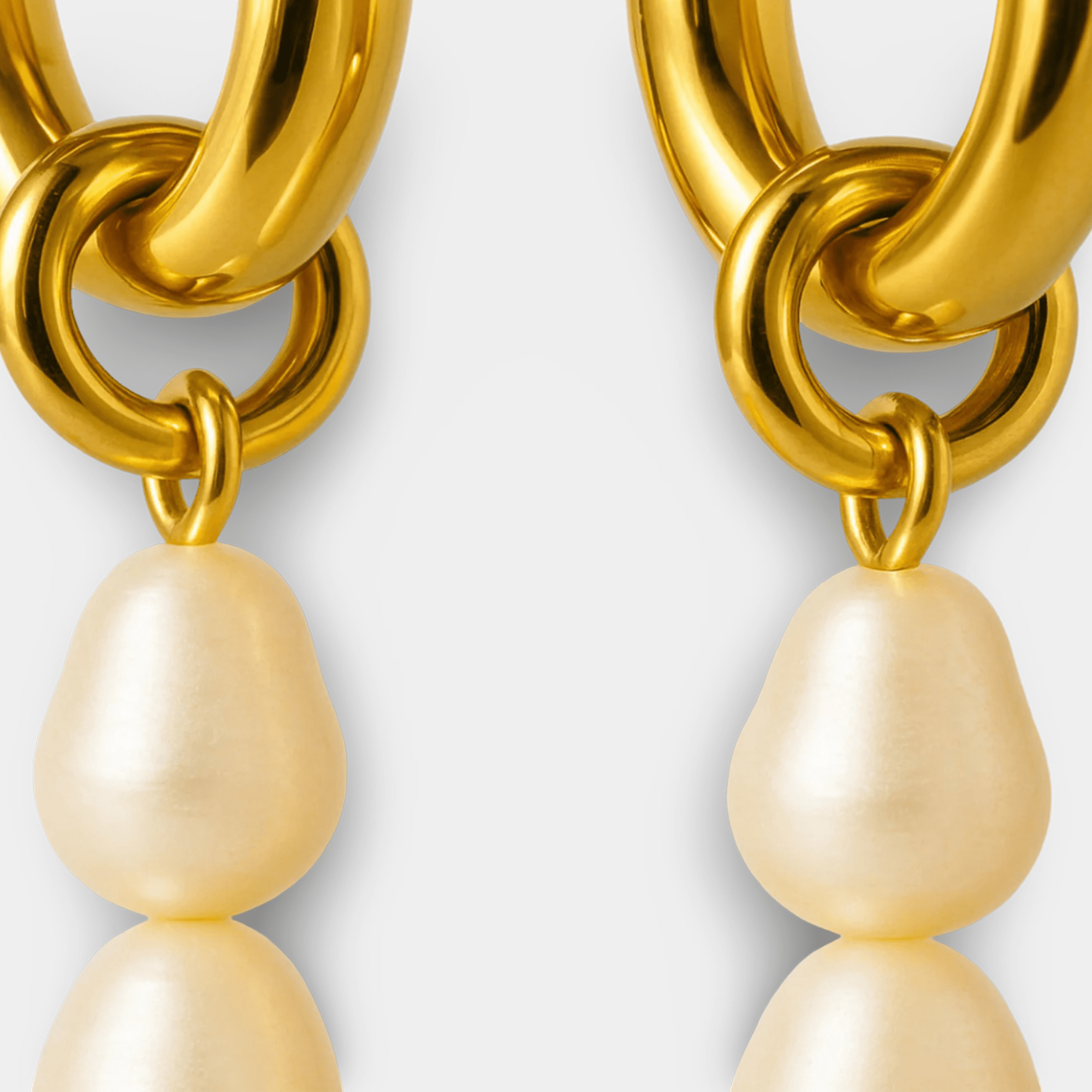Macro detail of the 18K gold plated hoop and pearl connector showing the smooth PVD gold finish