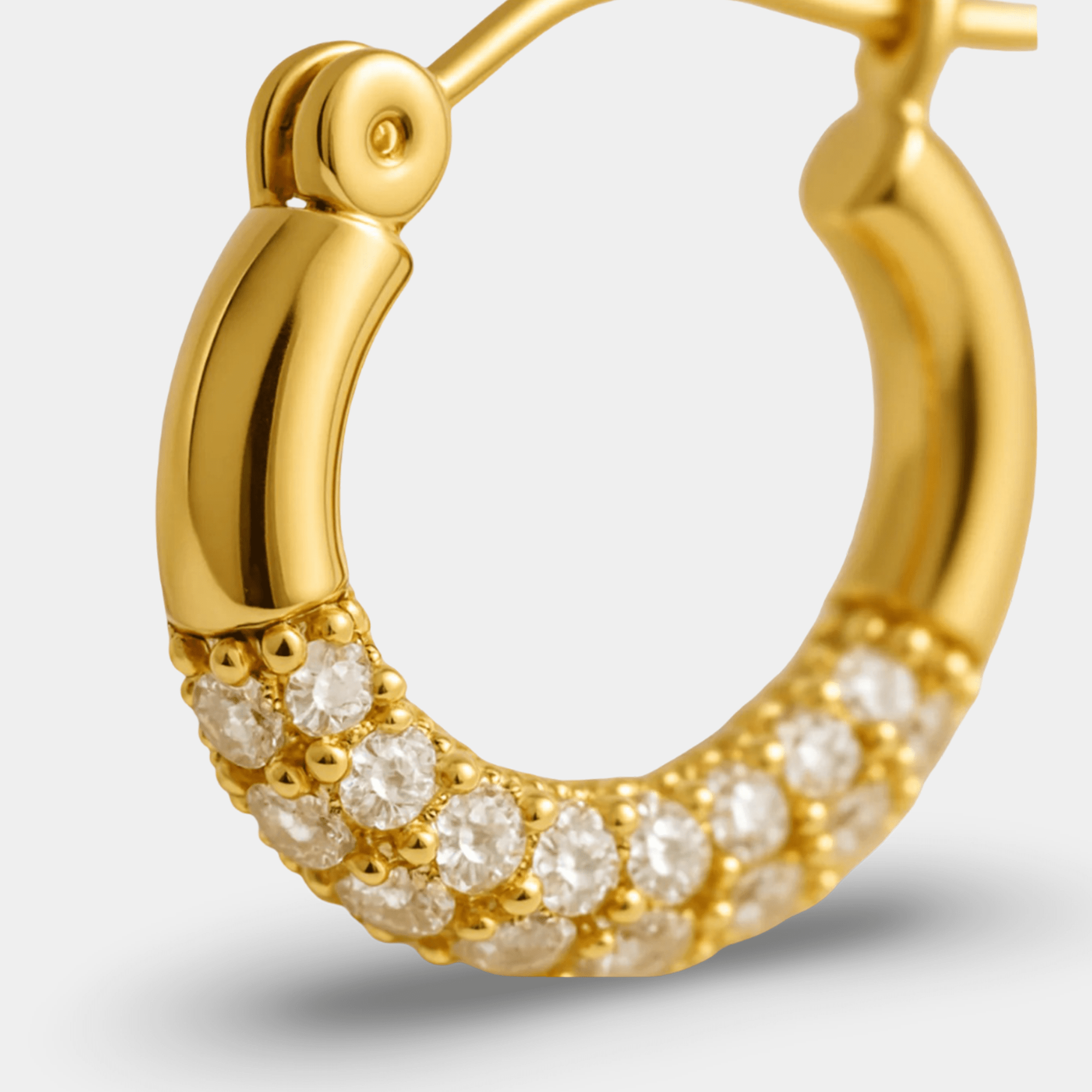 Macro close-up of the hinged snap closure and rhinestone pavé rows on a gold hoop earring