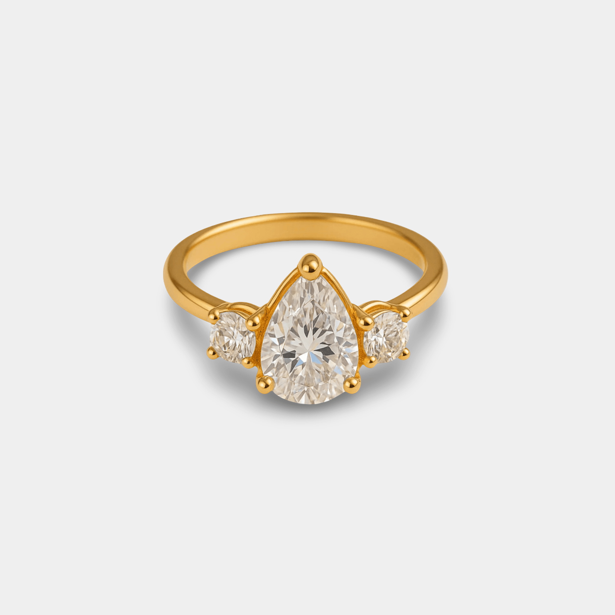 Close-up of the prong-set pear-cut cubic zirconia and round side stones on the gold three-stone ring