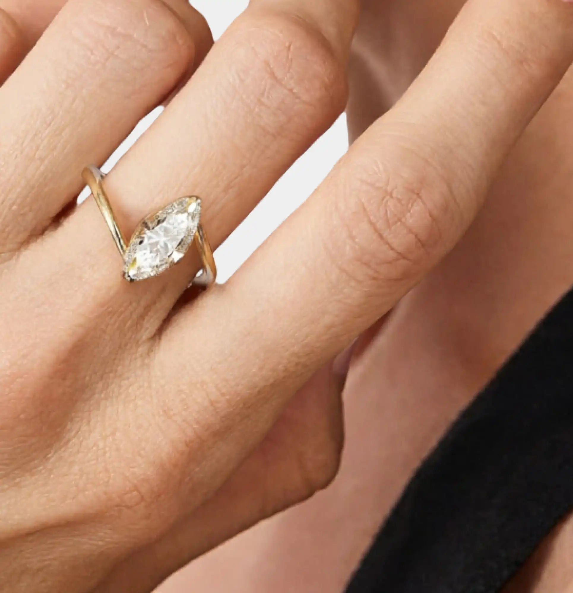 Close-up of a gold plated marquise engagement ring worn on a woman's hand