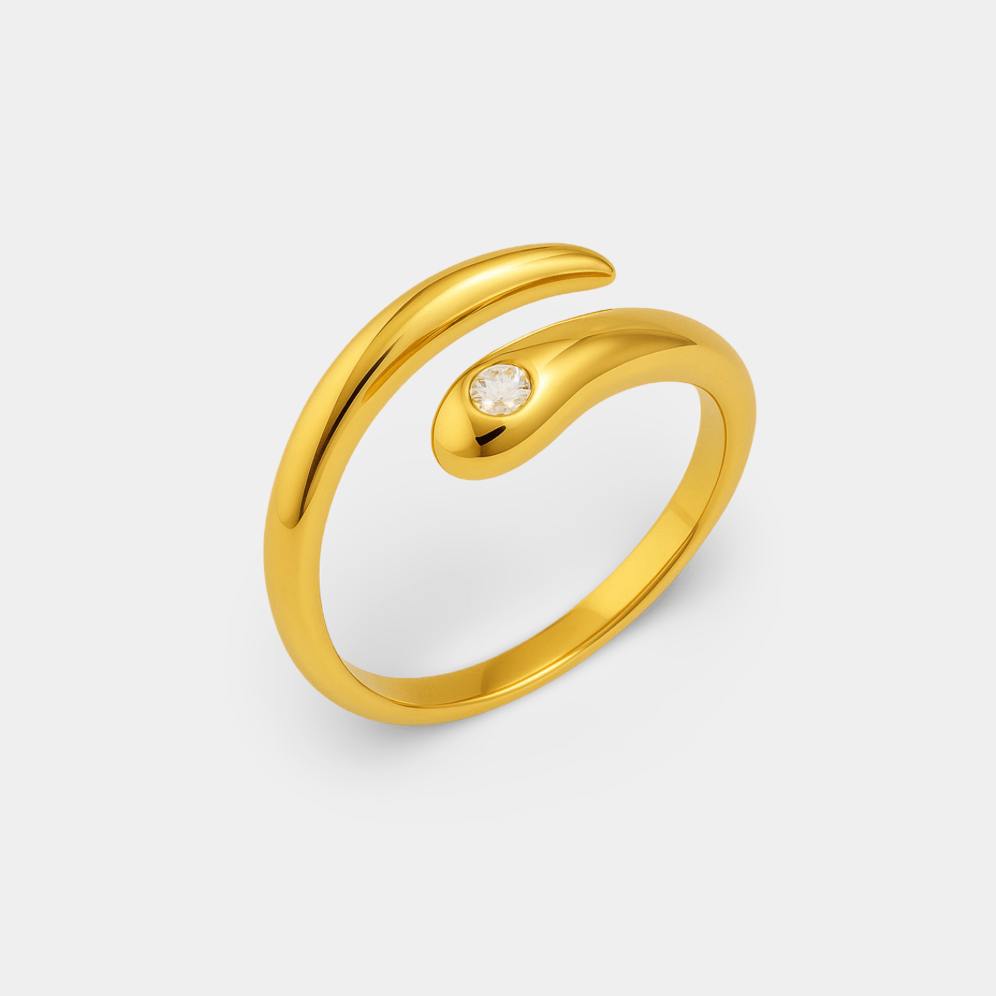 Side angle of the gold open wave wrap ring with a sparkling cubic zirconia accent on a light gray background