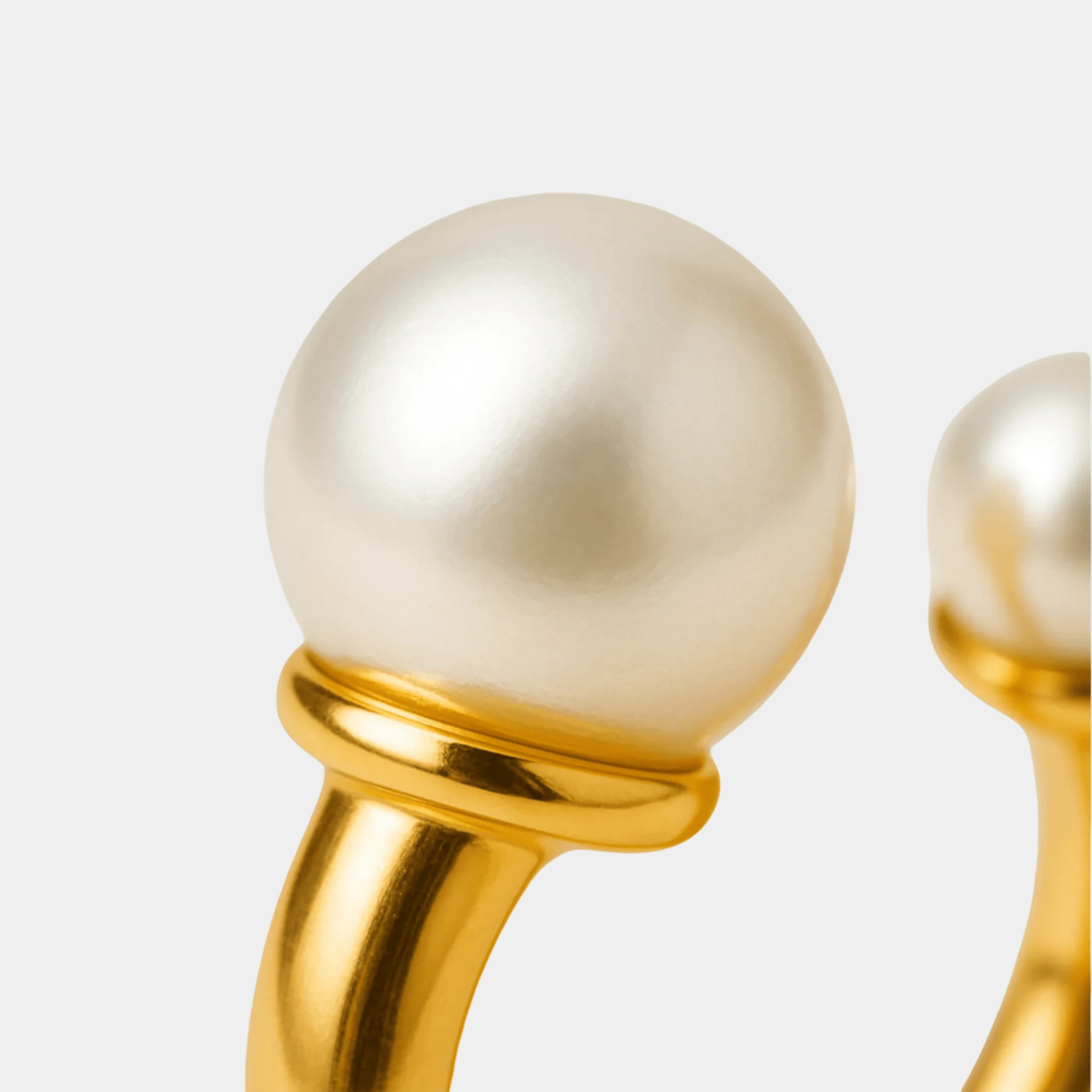 Twin pearl arc ring worn on a woman's hand showing the adjustable open fit