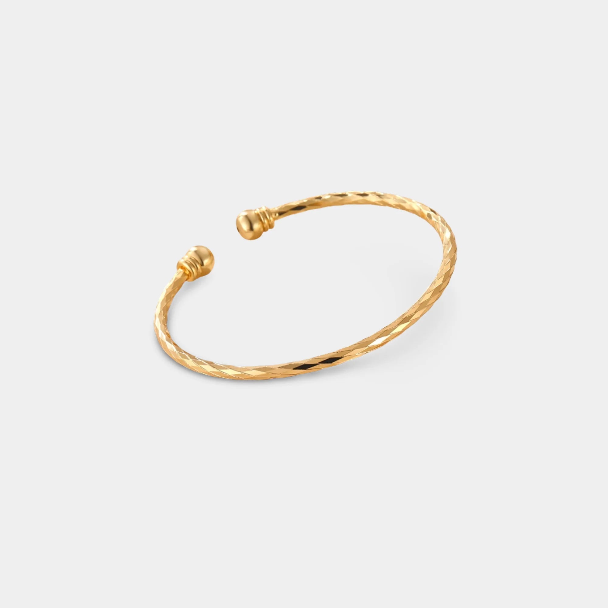 Close-up of the polished rounded end on a gold cuff bracelet