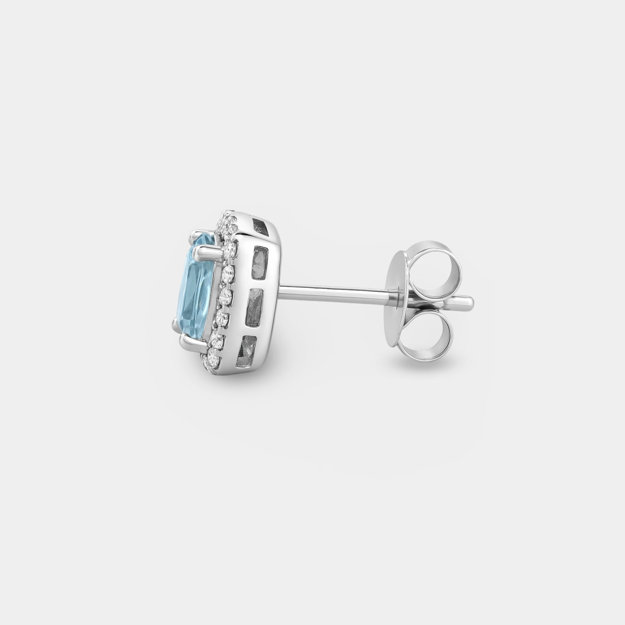 Side profile of one aquamarine halo stud earring showing the sterling silver post and butterfly push-back